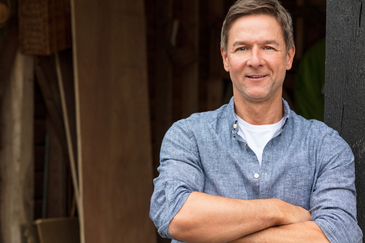 Man smiling, standing with arms folded across chest